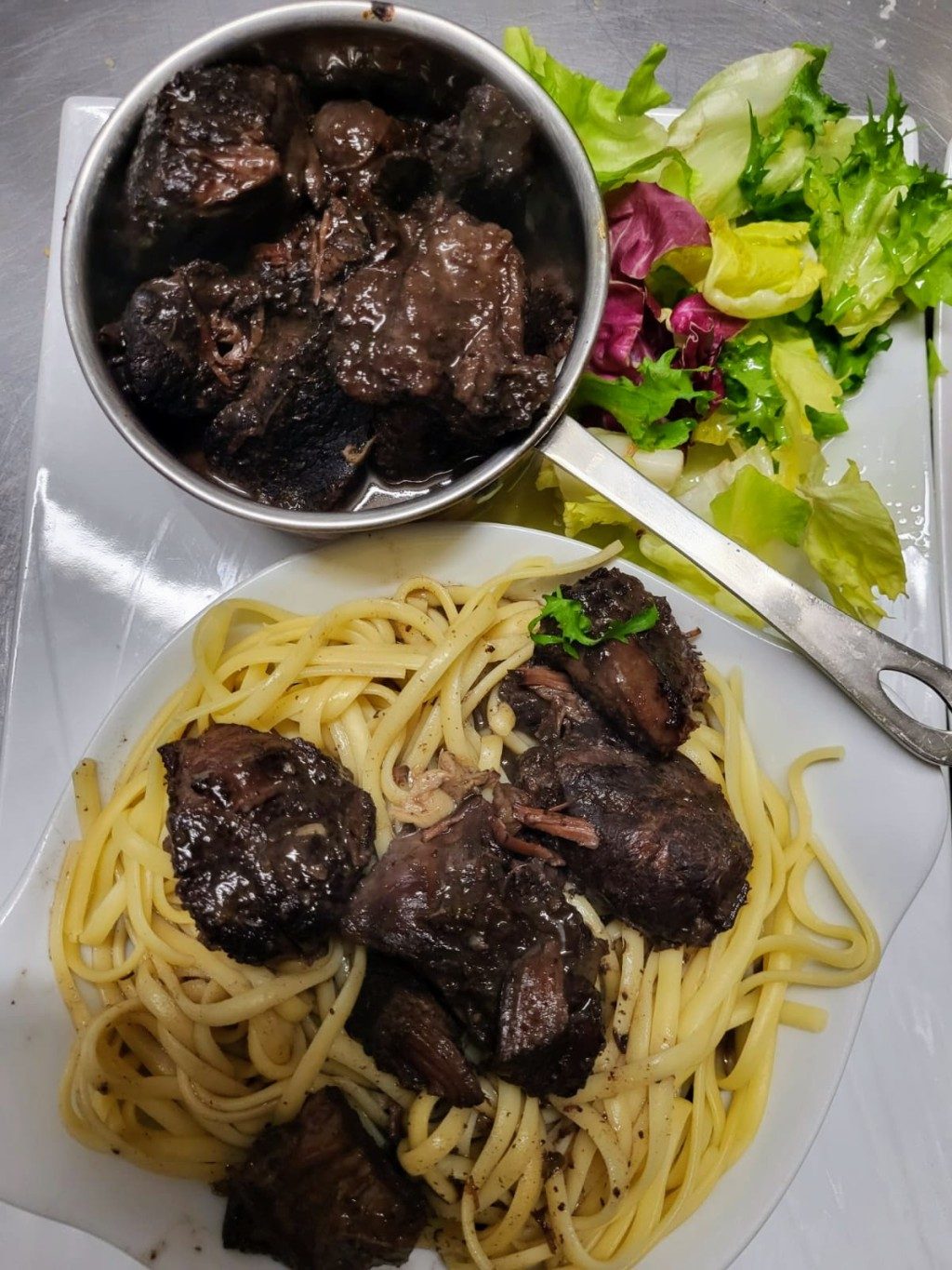 Des pâtes en sauce avec de la viande mijotée, et une salade
